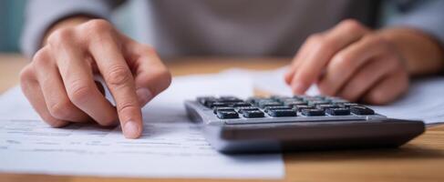 The focused hands calculating financial figures with a calculator on paperwork. photo
