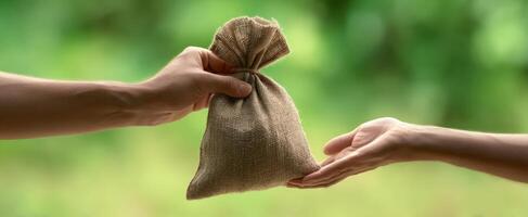 The hands exchanging a small burlap bag filled with valuable contents. photo