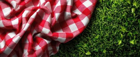 The classic red and white picnic blanket resting on fresh green grass. photo