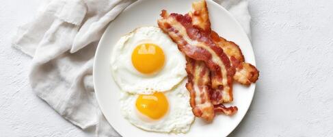The delicious combination of crispy bacon and fried eggs on a plate. photo
