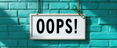 The humorous Oops sign on a vibrant turquoise brick wall photo