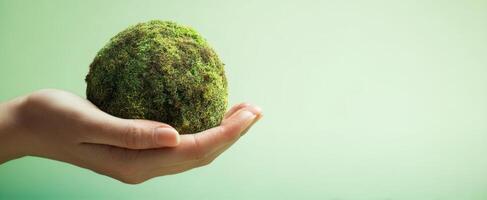 The hand holding a moss-covered globe representing environmental consciousness and sustainability. photo