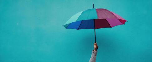 The colorful umbrella against a vibrant blue wall showcasing joy and protection. photo
