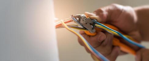 The electrician's hands expertly using pliers to connect colorful wires. photo