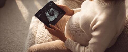 The Pregnant Woman Joyfully Reviewing Her Ultrasound on a Tablet. photo