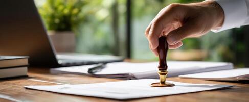 The hand applying a seal to an important document in an office setting. photo