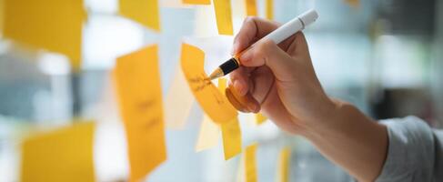 The hand writing on a vibrant sticky note in a modern workspace. photo