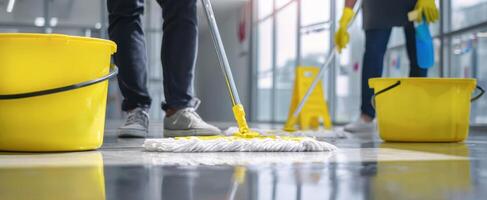 The professional cleaning team mopping a shiny office floor with yellow equipment. photo