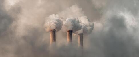 The towering smokestacks releasing emissions into a hazy atmosphere photo