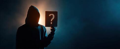 The enigmatic figure holding a question mark sign in a dramatic lighting setup. photo