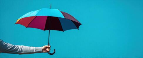 The colorful umbrella held against a pristine blue background showcasing vibrant design. photo