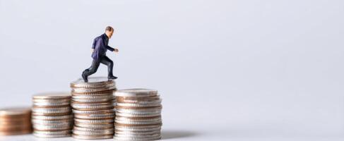 The miniature businessman climbing stacks of coins representing financial success. photo