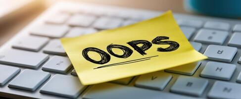 The sticky note saying Oops placed on a computer keyboard. photo
