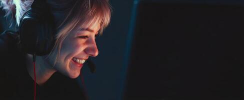 The smiling girl enjoying gaming on her computer with headphones. photo