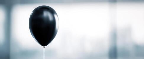 The black balloon floating in a minimalistic blurred background setting. photo