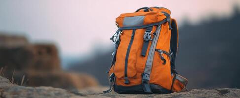 The vibrant orange backpack resting on a rock in a serene outdoor setting. photo