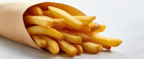 The delicious golden fries served in a paper cone on a clean surface. photo