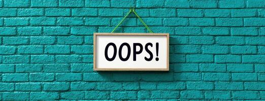 The word oops hanging on a brick wall photo