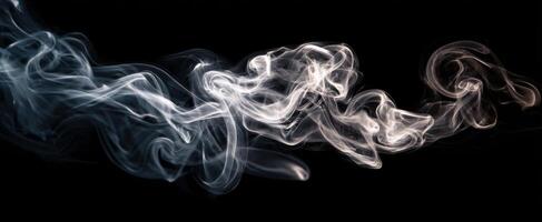 The delicate movement of smoke swirling elegantly in the darkness. photo