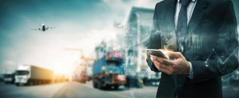 The businessman using a smartphone in a bustling logistics and transportation hub. photo