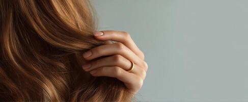 The hand gently holds the flowing hair with a golden ring. photo