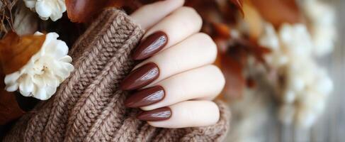 The elegant brown manicure against a cozy autumn backdrop with flowers. photo