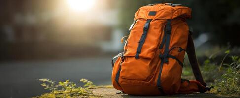 The vibrant orange backpack resting on a path during sunset. photo