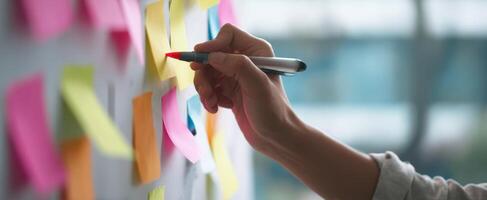 The hand writing on colorful sticky notes in an office brainstorming session. photo