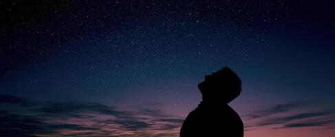 The silhouette of a person gazing at a starry night sky with wonder. photo