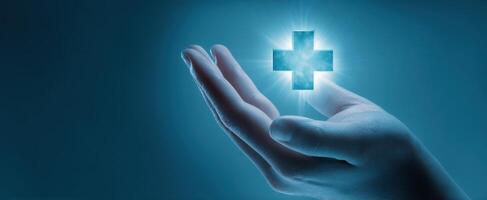 The hand holding a glowing medical cross symbol in a caring gesture. photo