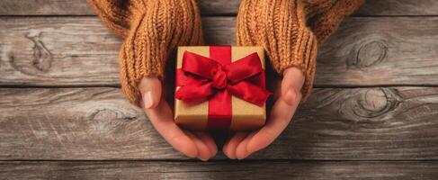 The hands holding a beautifully wrapped gift with a festive ribbon. photo
