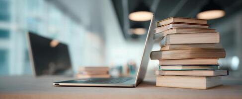The laptop next to a neatly stacked collection of books in a modern workspace. photo
