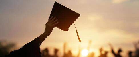 The graduation cap held high in celebration at sunset. photo