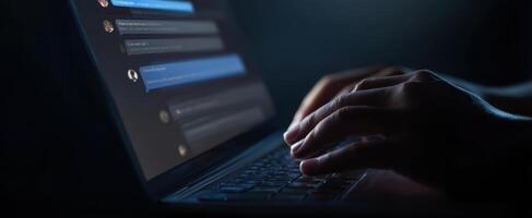 The laptop keyboard illuminated by hands typing in a dark environment. photo