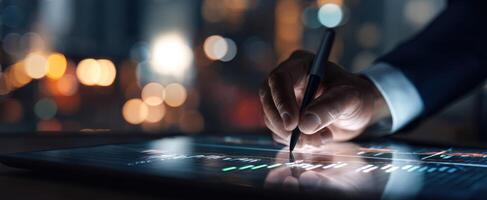 The business professional analyzing financial data on a touchscreen tablet at night. photo