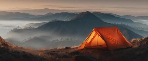 The vibrant orange tent overlooking misty mountains at sunrise photo