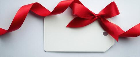 The elegant red ribbon tied to a blank gift tag on a minimalistic background. photo