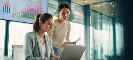 The women collaborating on a laptop with financial data and graphs in the background. photo