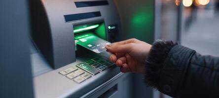 The hand using an ATM card at an illuminated automated teller machine. photo