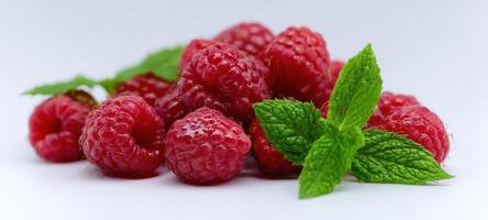 The vibrant raspberry pile complemented by fresh mint leaves on a white background. photo