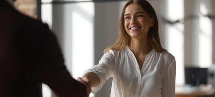 The smiling woman engaging in a handshake during a professional business meeting. photo