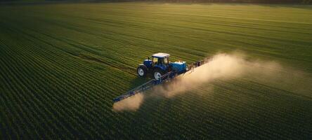 The tractor spraying pesticide over a vast green field during sunset. photo