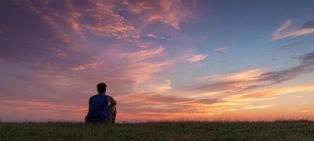 The Person Sitting Alone Enjoying a Serene Sunset in Nature photo
