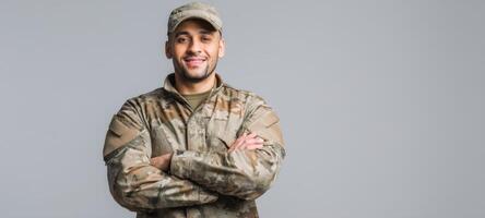 The soldier smiling confidently in military uniform against a neutral background. photo