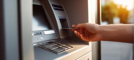 The hand inserting a card into an ATM for a transaction during sunset. photo