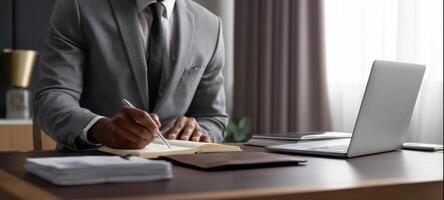 The businessman writing in a notebook at a stylish modern office desk. photo