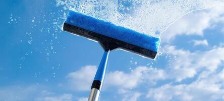The squeegee glistens with bubbles against a bright blue sky. photo