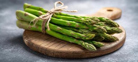 The fresh asparagus tied with string on a rustic wooden board. photo