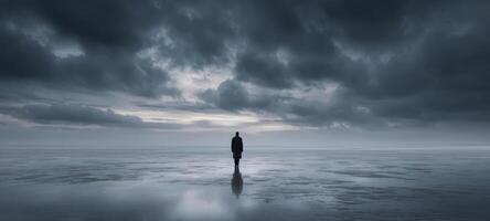 The solitary figure stands still against the dramatic ocean landscape at dusk. photo