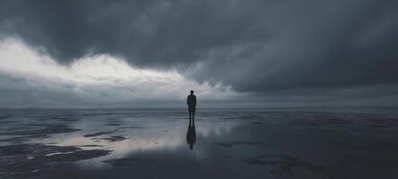 The solitary figure standing still on a reflective shoreline under dark skies photo
